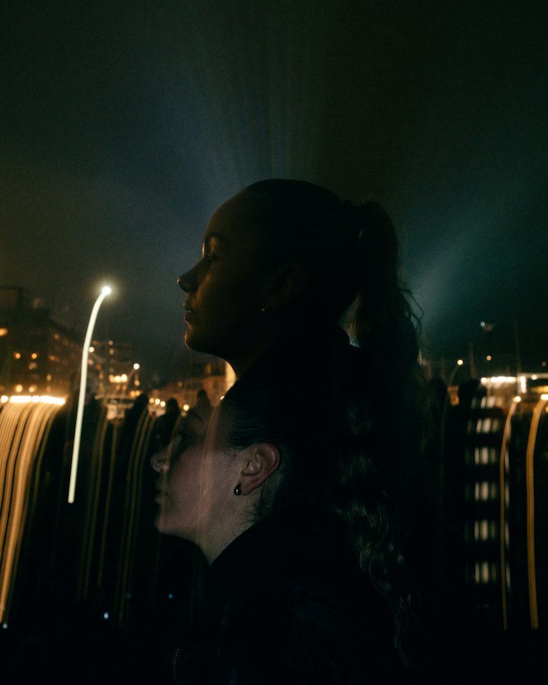 Silhouetted figures against blurred city lights at night creating moody atmosphere
