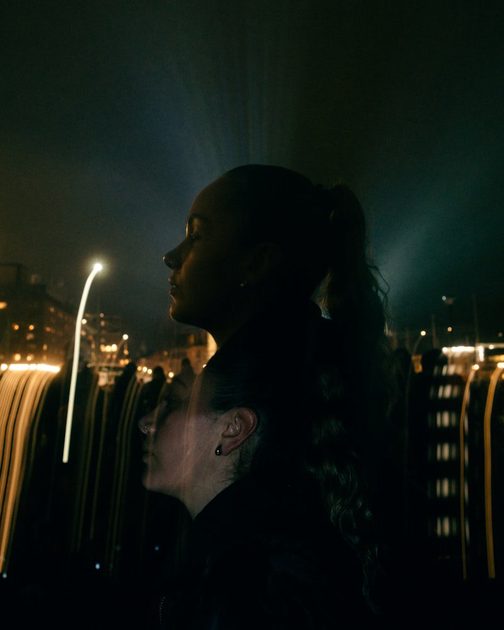 Silhouetted figures against blurred city lights at night creating moody atmosphere