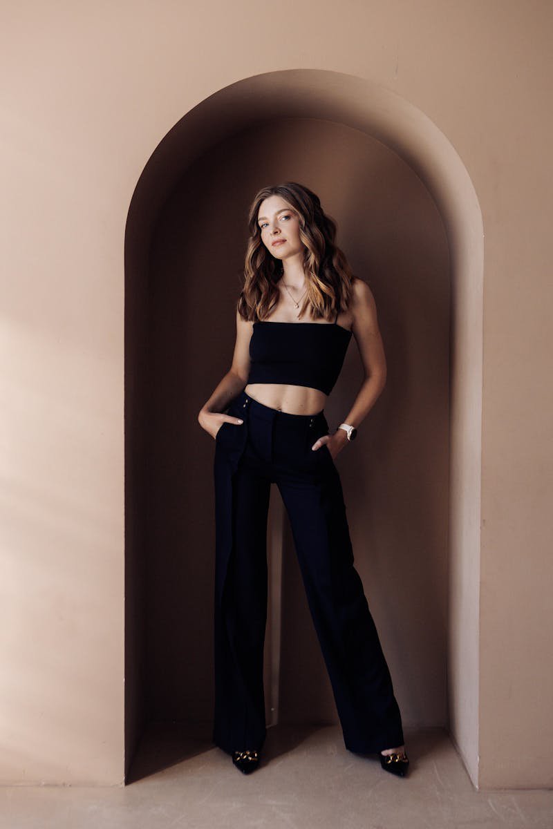Stylish woman in modern neutral outfit posing in an elegant arched hallway