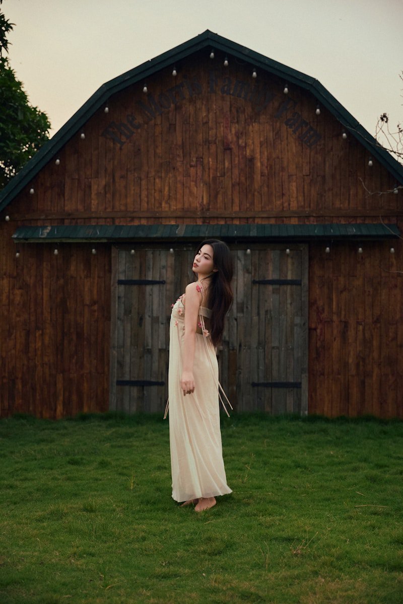 Woman in a long flowing dress standing in a pastoral countryside setting at golden hour