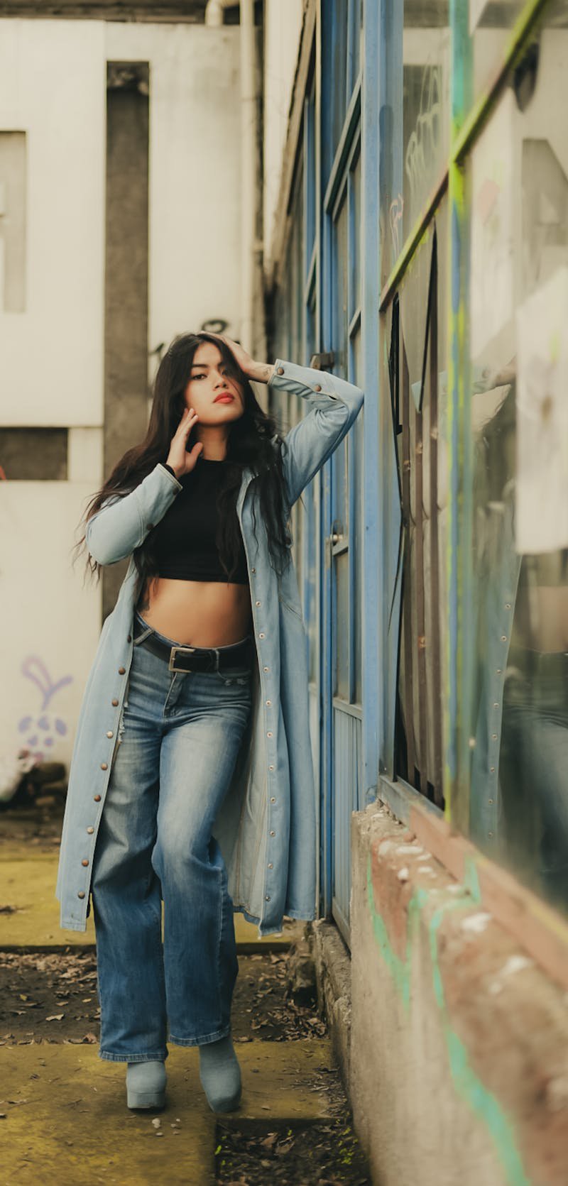 Fashionable woman in creative denim outfit posing confidently in an urban outdoor setting