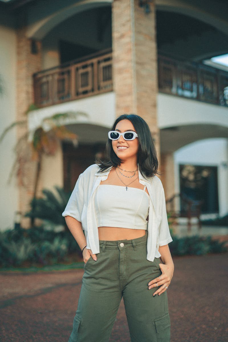 Young woman in casual summer outfit with sunglasses posing outdoors on a sunny day