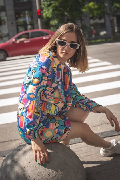 Stylish woman in colorful summer outfit posing confidently on an urban street