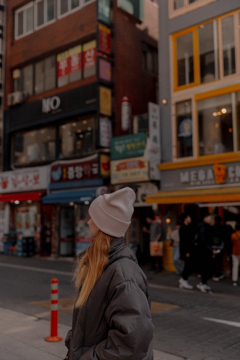 Young woman in chic casual outfit standing in a colorful urban Asian street setting